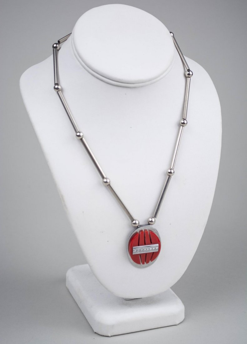 Jakob Bengel Chrome and Galalith Necklace: Chrome tubular beads suspending a red galalith and chrome oval pendant. Length 18 inches. Notice to bidders: Condition reports and additional photographs are provided by request as a courtesy to our c