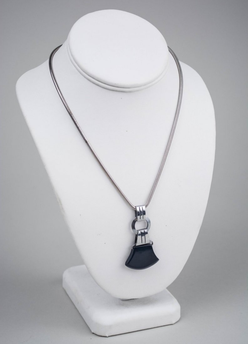 Jakob Bengel Chrome and Galalith Necklace: Chrome snake chain suspending a chrome and dark blue galalith pendant. Length 18 inches. Notice to bidders: Condition reports and additional photographs are provided by request as a courtesy to our cl