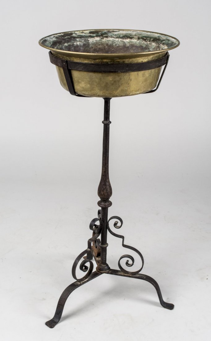 Iron and Brass Plant Stand: Circular brass dish in a scrolled iron stand with tripod base. Height 35 inches, diameter 16 1/2 inches. Notice to bidders: Condition reports and additional photographs are provided by request as a co