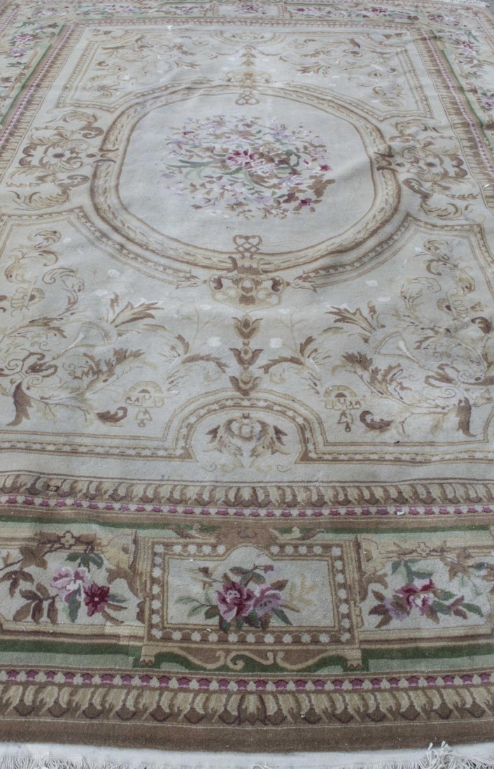 Aubusson Style Rug: Central floral medallion on a tan field within a green, tan and brown border with similar floral decoration. 12 feet x 9 feet. Notice to bidders: Condition reports and additional photographs are provi