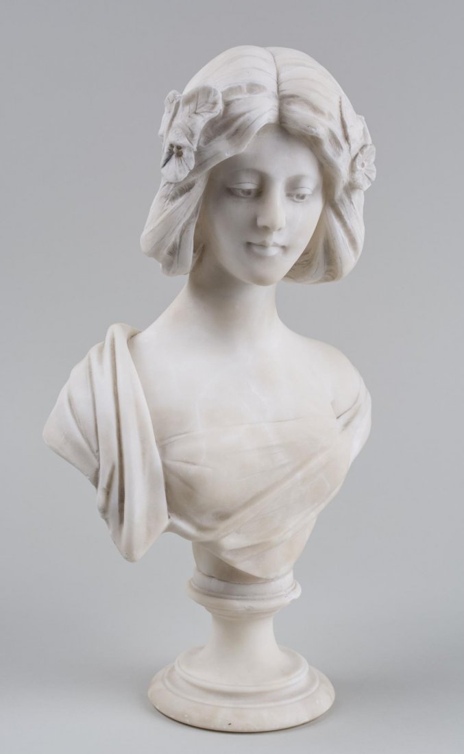 Marble Bust of Young Woman: Classical style woman facing forward and gazing downward, shawl draped over her right shoulder. Height 17 inches. Notice to bidders: Condition reports and additional photographs are provided by reques