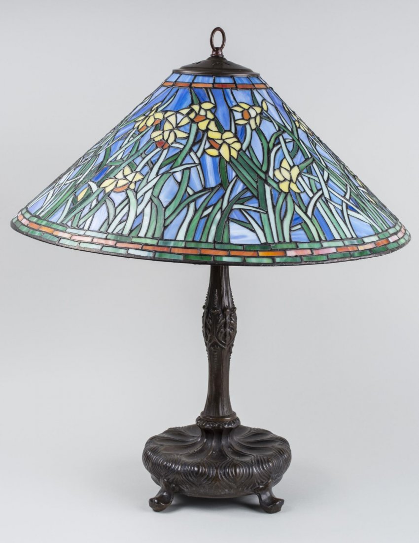 Tiffany Style Lamp: Leaded glass shade decorated with Irises, patinated bronze base. Height 26 1/2 inches, shade diameter 21 inches. Notice to bidders: Condition reports and additional photographs are provided by request