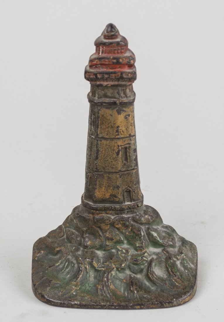 Cast Iron Lighthouse Doorstop: Polychrome painted decoration. Height 7 1/2 inches. Notice to bidders: Condition reports and additional photographs are provided by request as a courtesy to our clients, as such any condition report i
