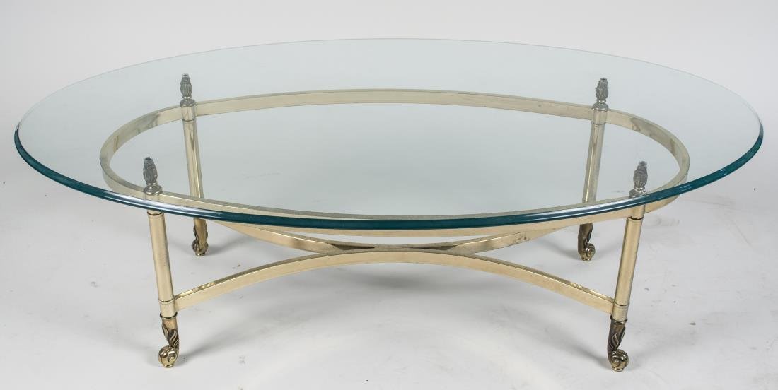 Glass Top Brass Coffee Table: Oval glass top, base with tubular legs. Height 16 inches, width 42 inches, depth 26 inches. Notice to bidders: Condition reports and additional photographs are provided by request as a courtesy to our
