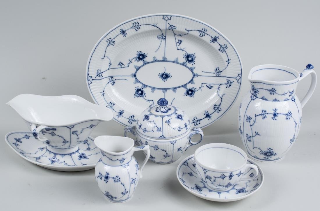 Royal Copenhagen Porcelain Partial Dinner Service: Blue fluted plain pattern, comprising sixteen bowls, three cups, two saucers, six salad plates, a serving bowl, three small oval platters, a sauceboat, a covered sugar bowl, a creamer, a pitcher, six 