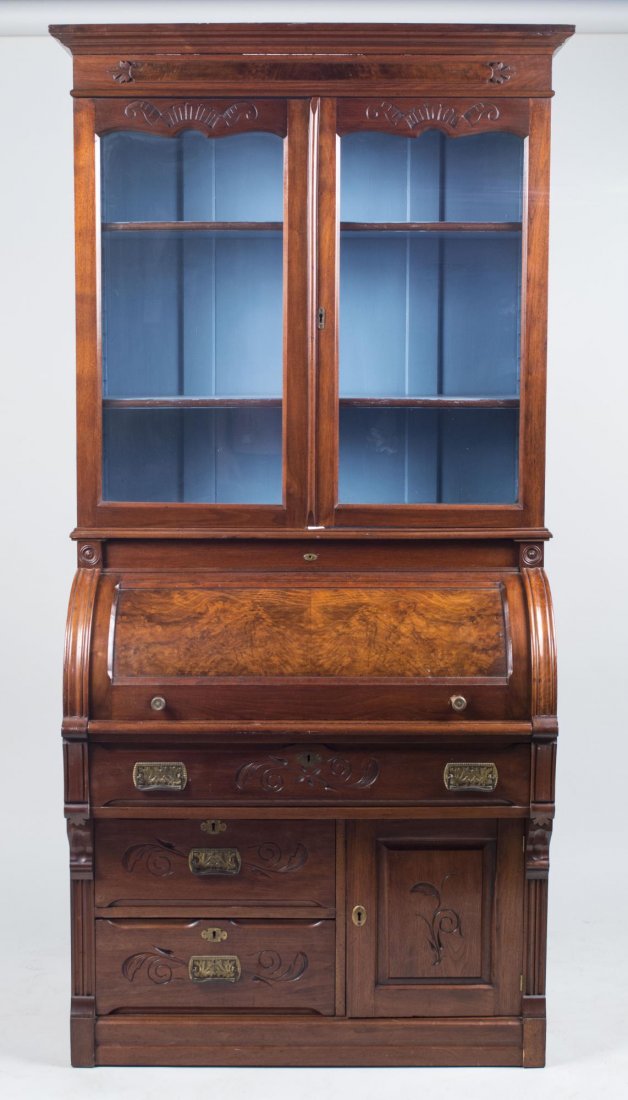 Roll Top Secretary: Rectangular overhanging molded top above two glazed doors opening to shelves, above a roll top desk with fitted interior and pull out writing surface, above a single long drawer, two short drawers and