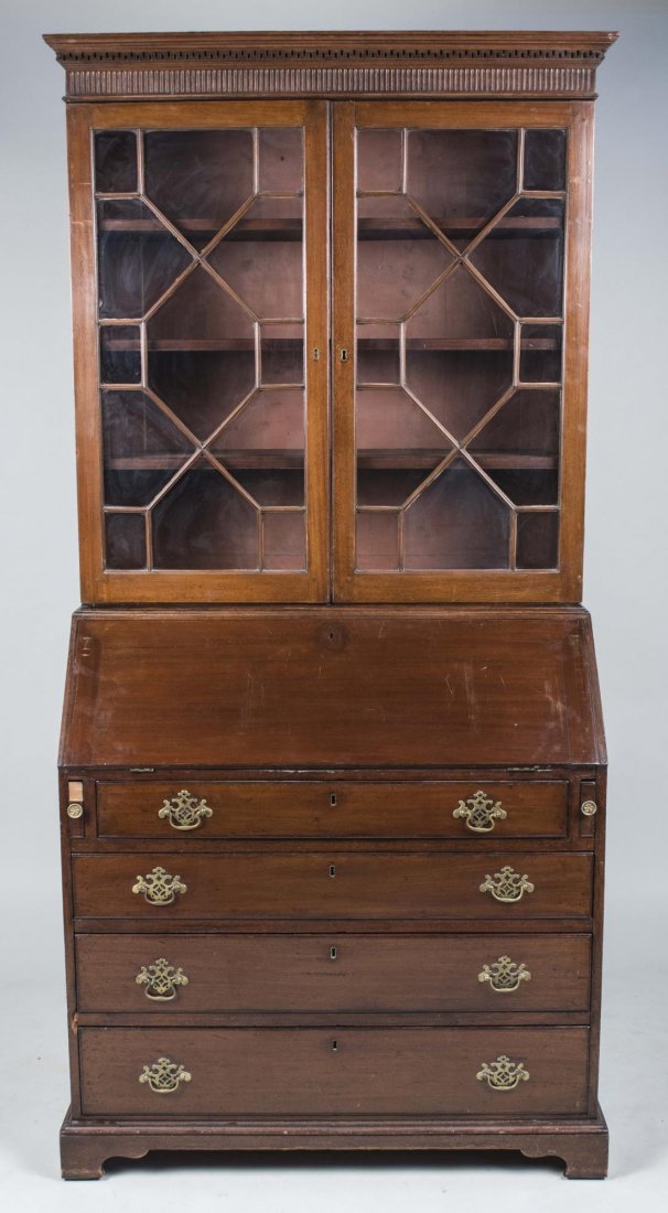 Georgian Style Mahogany Secretary: Molded cornice over two glazed doors opening to four shelves, above a slanted desk and four graduated drawers, bracket feet. Height 6 feet 2 inches, width 37 inches, depth 21 inches. Provenance: Warre