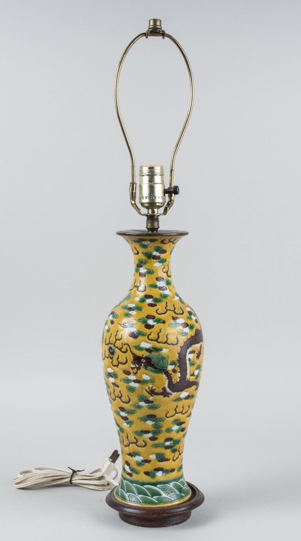 Asian Porcelain Lamp: Vase form lamp decorated with dragons and clouds on a yellow ground. Height 15 inches. Notice to bidders: Condition reports and additional photographs are provided by request as a courtesy to our clie