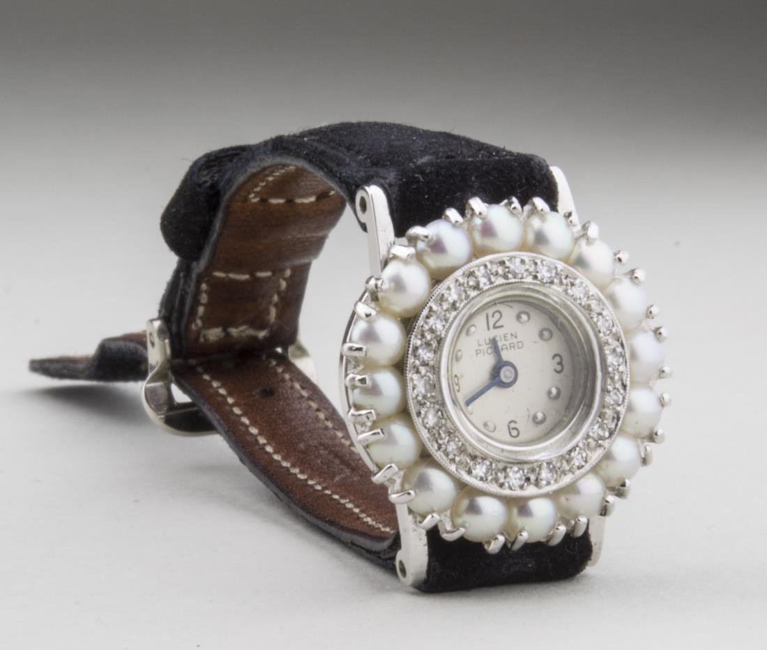 Lucien Piccard Lady's Wristwatch: White dial with Arabic quarter hours, within diamond and cultured pearl bezels, black suede band,w original box. Notice to bidders: Condition reports and additional photographs are provided by request