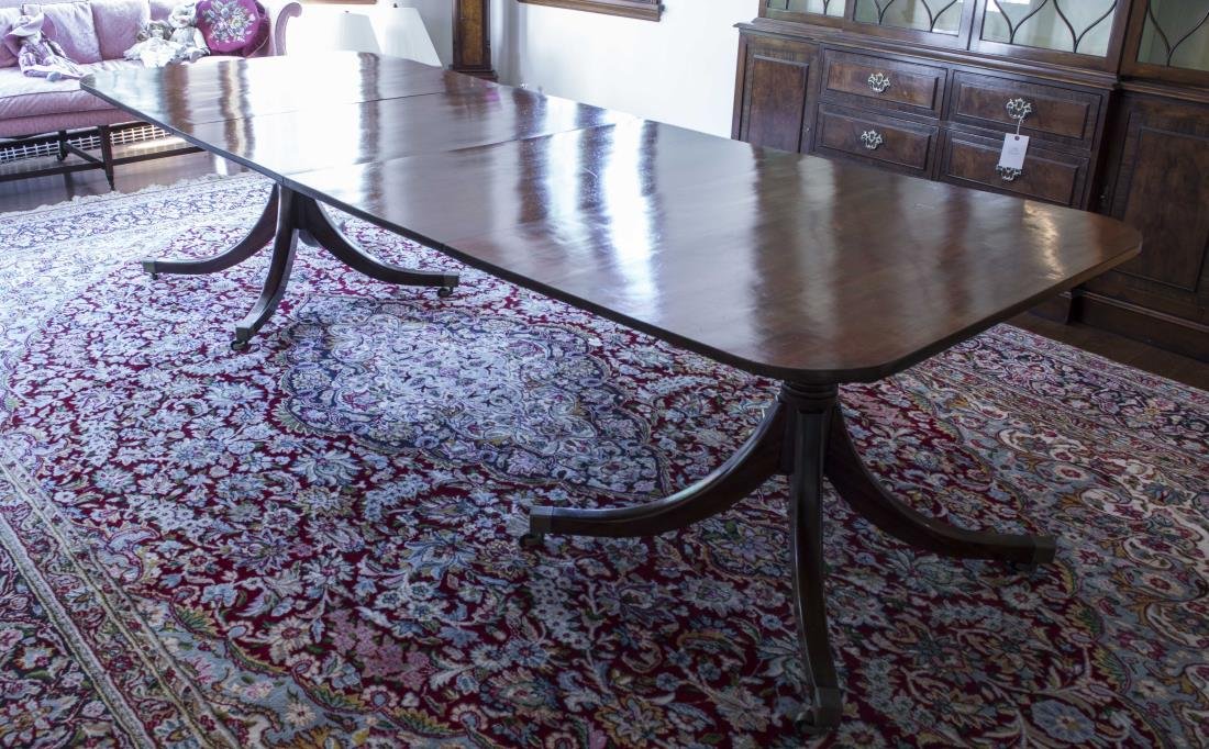 English Mahogany Two Pedestal Dining Table: 19th Century, rectangular top with rounded corners, on turned pedestals issuing four downswept legs ending in brass caps and casters, two leaves. Height 28 inches, length 9 feet 9 inches, depth 44 1/2