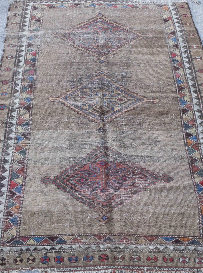 Persian Style Carpet: Three geometric center medallions on a tan field, within a multi colored border with similar geometric decoration. 5 feet 8 inches x 3 feet 8 inches. Notice to bidders: Condition reports and additiona