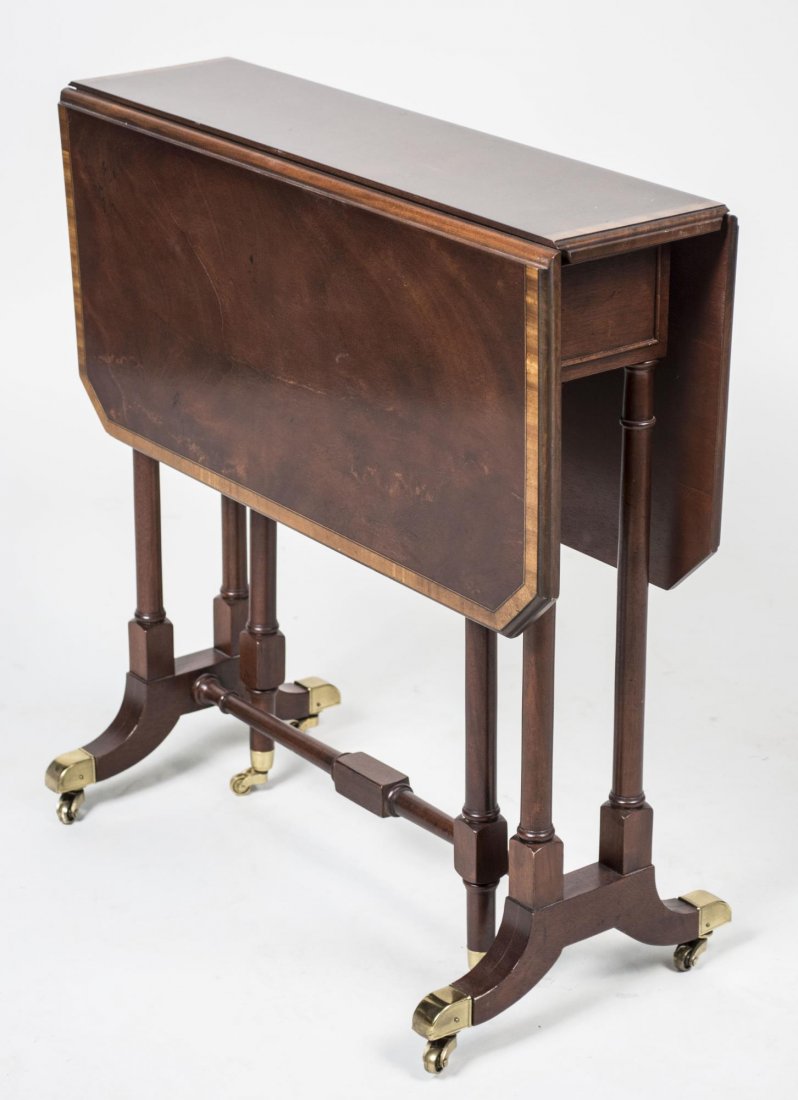 Mahogany Sutherland Style Drop Leaf Table: Rectangular top with crossbanded edge, flanked by two drop leaves, on a turned trestle base. Height 25 inches, width 28 inches, depth 24 inches. Notice to bidders: Condition reports and additional pho