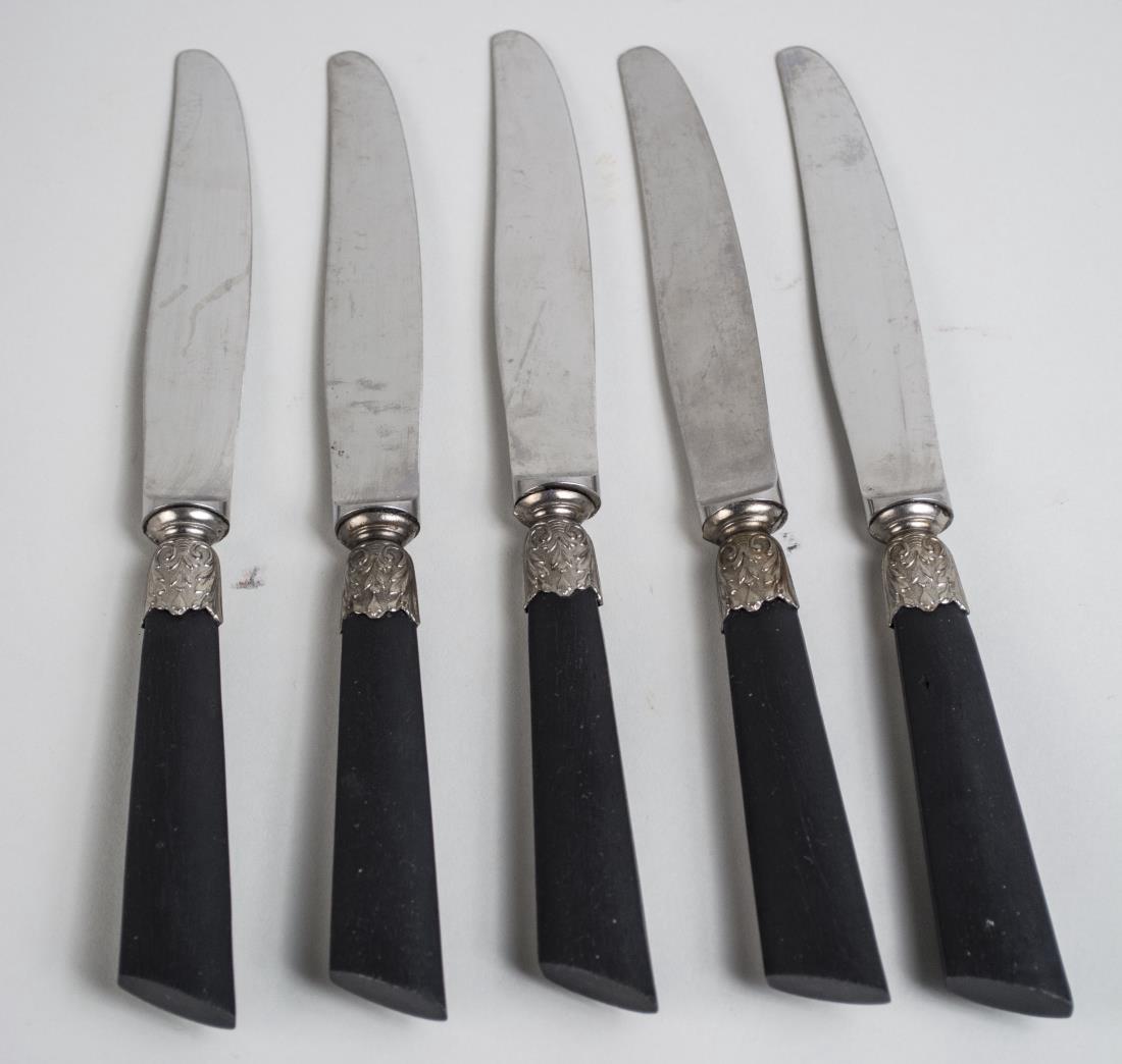 Set of Twelve Ebony Handled Dinner Knives: Acanthus leaf decorated sleeves. Length 10 inches. Notice to bidders: Condition reports and additional photographs are provided by request as a courtesy to our clients, as such any condition report is