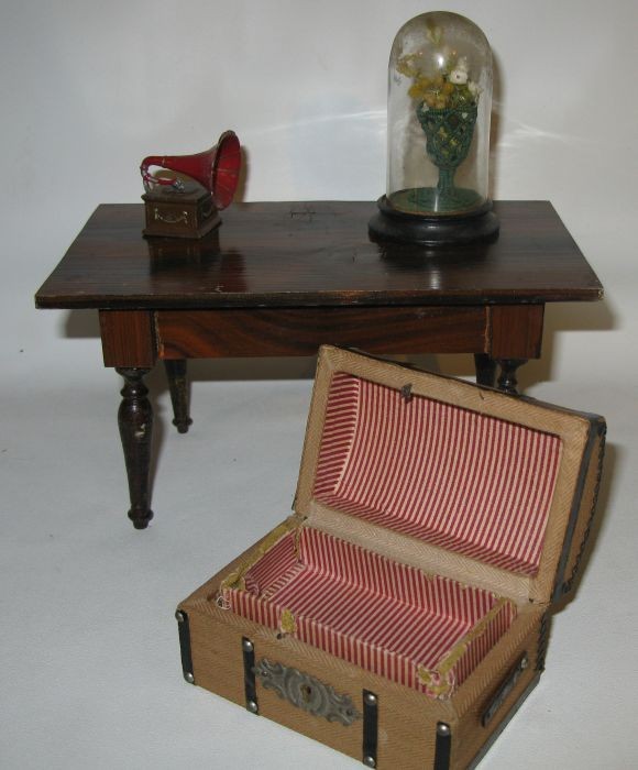 Four pieces of doll house furnishings: including a wooden grain-painted table, 4 3/4" x 8 1/4" x 4 1/2" high, victrola, plant under glass, and a trunk.