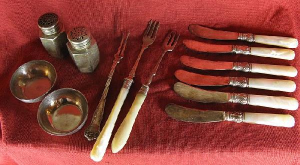 Thirteen pieces of silver tableware: including: two silver pepper shakers, two sterling salt cellars, six pearl-handled & sterling butter knives, two pearl-handled pickle forks, and a sterling pickle fork.