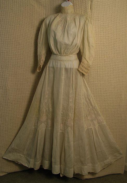 Victorian Lawn Dress Circa 1905: Exceptional ivory cotton lawn dress, with floral lily appliqués, satin stitch embroidery, ten panel gore skirt. Pin tucked bodice, cuffs, waist. Inset lace panels. Condition: few breaks at seams, ove