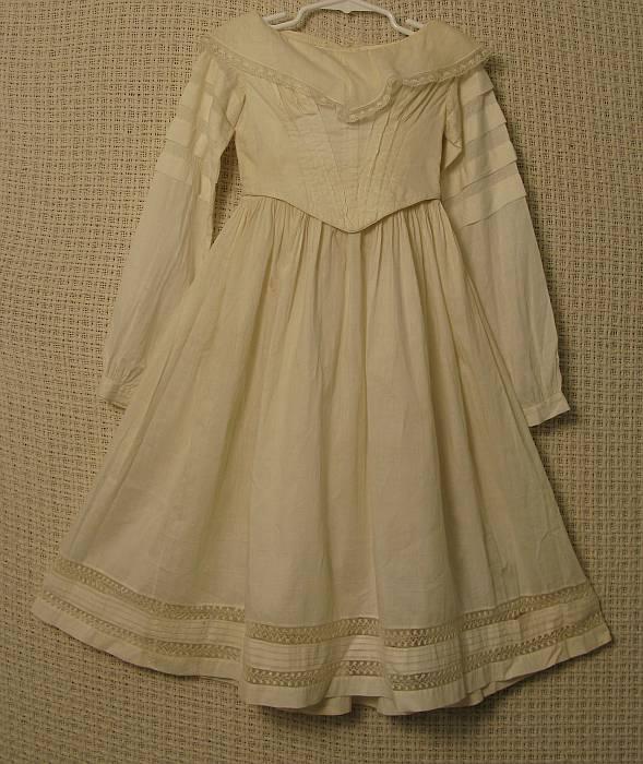 Victorian Girls White Cotton Gown: Tucked and padded pointed bodice, pleated sleeves, inset lace at hemline. Condition: VG. Belonged to Anna Louise Harrington wife of Nathan Green.