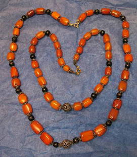 Pair 1920's Baltic Amber Necklaces: Beads are slightly graduated with hand wrapped brass wire rondelles and dark wood spacers. Lengths: 18" and 24 " . Brass filigree center bead & spring ring clasps. Cond: VG.(longer necklace could use