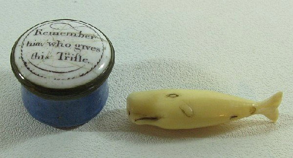 Two small objects: one is a Georgian enamel & brass pill box, 3/4" high, cover with aphorism "Remember him who gives this trifle."; and a miniature carved ivory whale, 1 1/2" long.