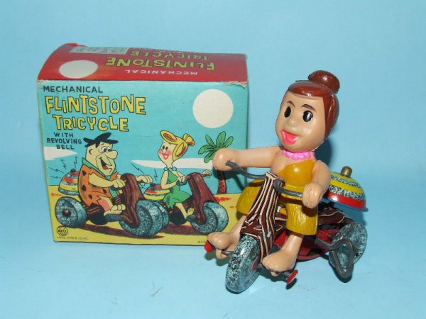 MARX WILMA FLINTSTONE TRICYCLE TIN WIND UP & BOX: 1962. USA. Working. Complete. All Original. Wilma is made of celluloid & her bike is made of tin with a working revolving bell. 4" L x 4.25" H. (NM). OB complete w/writing on box bottom flap. (NM).