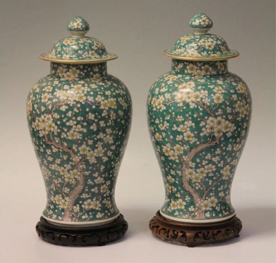 PAIR OF CHINESE PORCELAIN COVERED URNS: With cherry blossom decoration Height of urns- 18" Note- to be sold with stands, chip on one urn, on rim