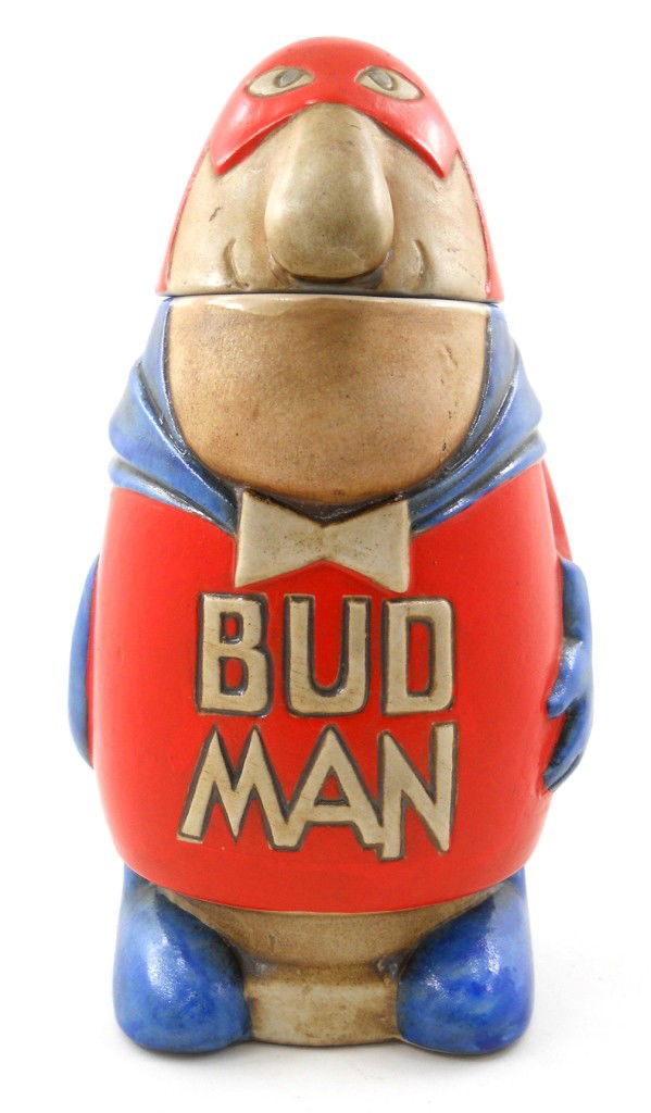 1975 Bud Man Beer Stein by Ceramarte: This fun little stein is an original 1975 Ceramarte Budman Beer Stein, made in Brazil for Budweiser. The comical man in a red and blue outfit features the unknotted bow tie, with the stein having a ho