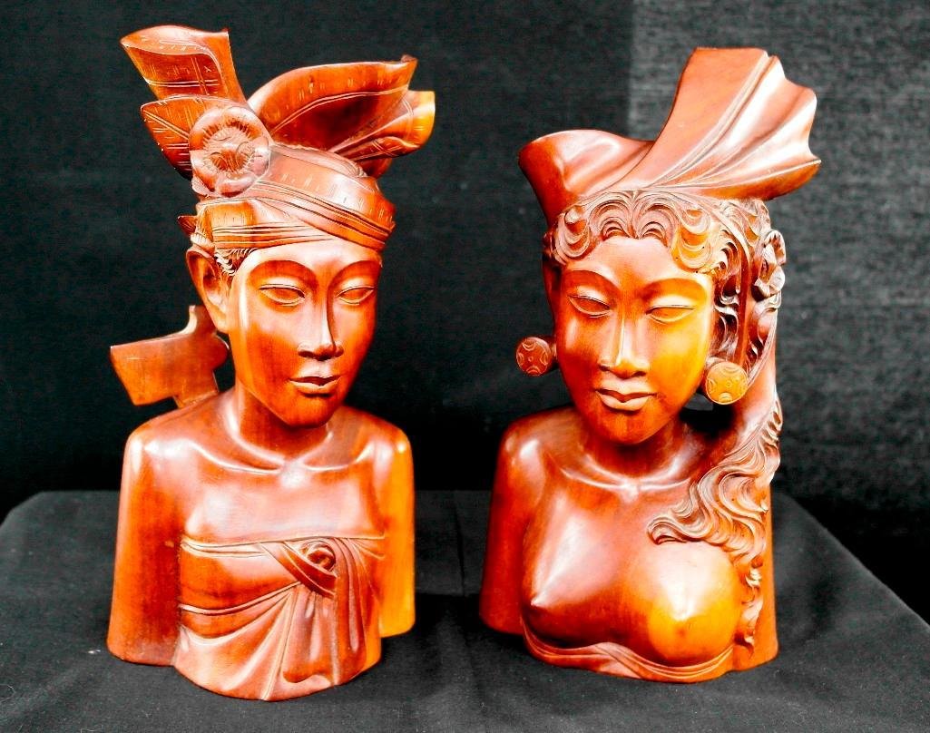 Pair of Carved Wooden Statue Busts - Balinese Females: This pair of wooden carvings depict a pair of Balinese women, complete with headdresses. One of the carvings has an axe tucked into the back of the carving - both carvings have great detail and are in