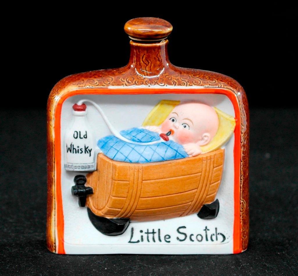 Vintage Schafer & Vater Color Hip Flask - Little Scotch: This vintage Schafer & Vater piece is a color hip flask. It is titled "Little Scotch" and depicts a small child in their crib - which is a halved whisky barrel - taking a sip from a bottle labeled "ol