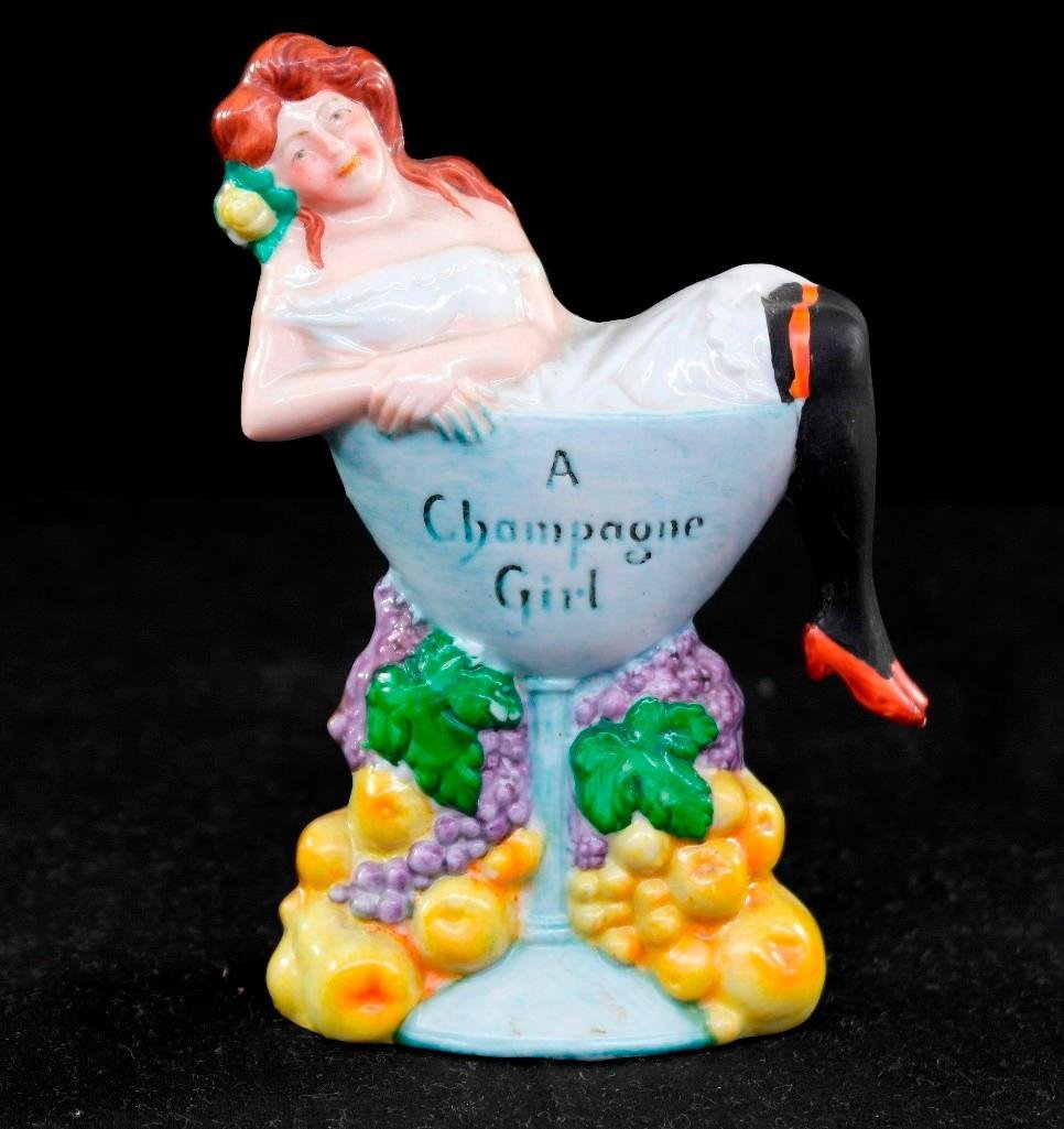 Vintage Schafer & Vater Colored Nipper Flask - A: This vintage Schafer & Vaterpiece is a colored nipper flask. It is titled "A Champagne Girl" and features a woman lounging in a glass of champagne. This piece comes with its original stopper and is in