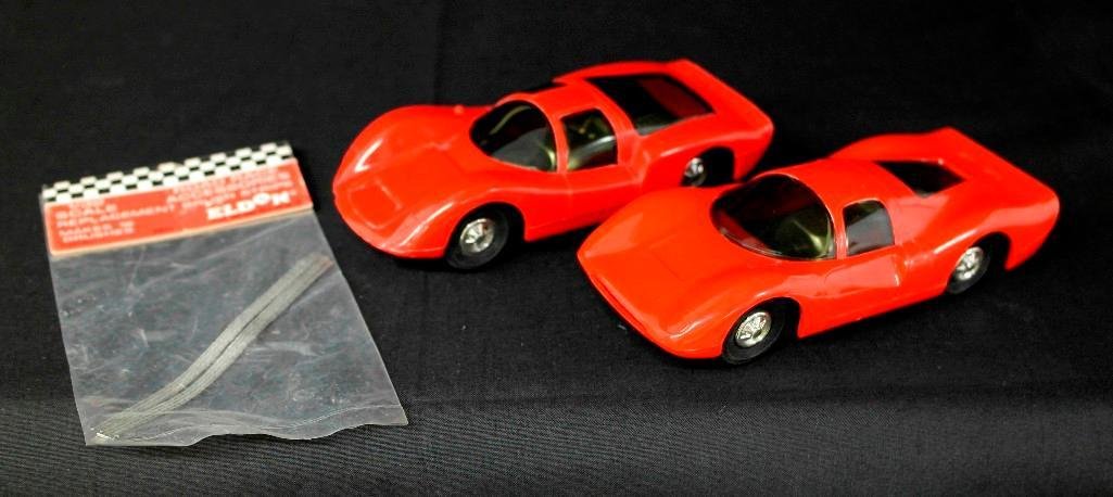 Set of 2 Vintage 1960s Eldon Slot Cars - 1/32 - Porsche: This set of two vintage Eldon 1/32 scale slot cars also comes with a pair of replacement brush strips in their original bag. The first car is a red Porsche Carrera, 1351-11, with an adjustable chassis