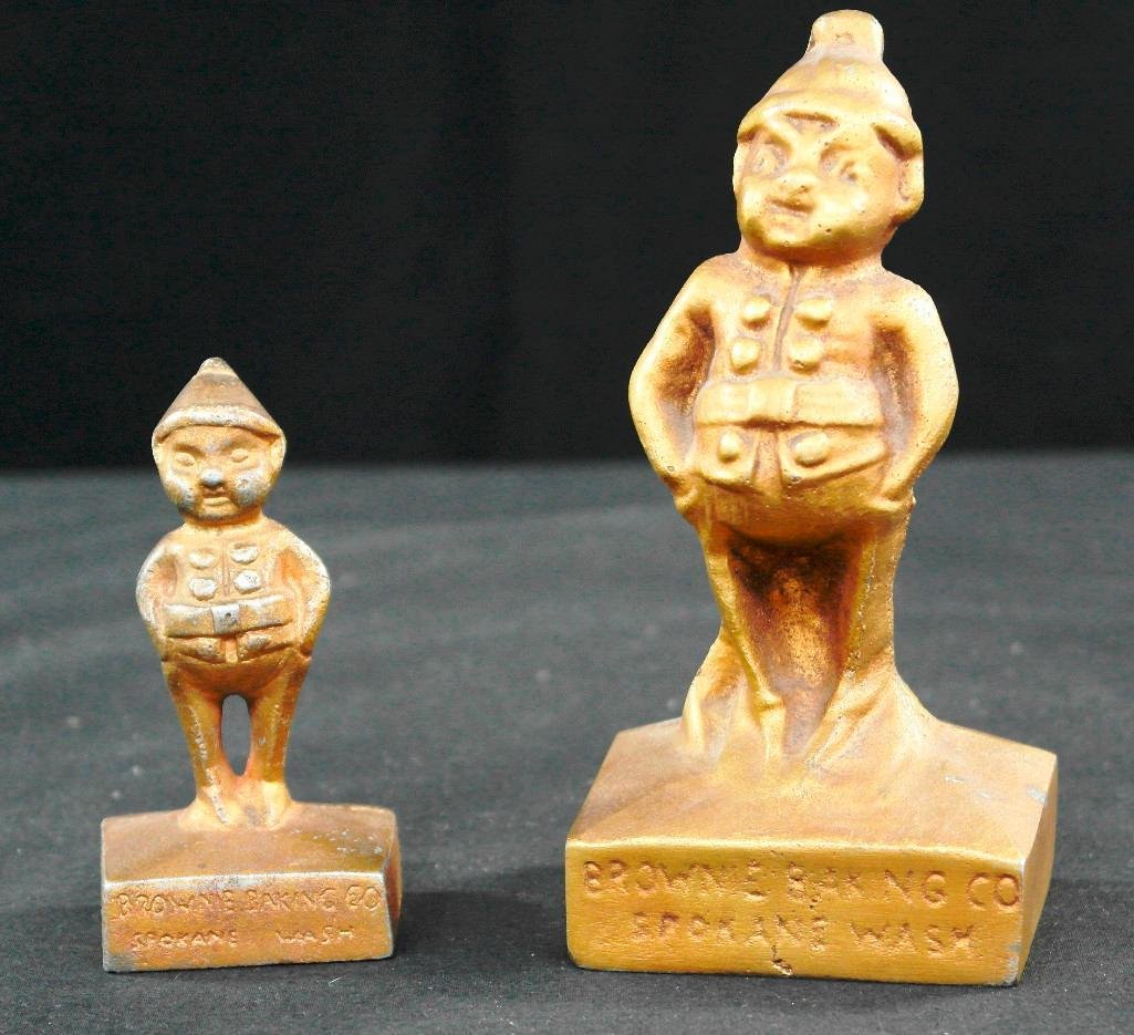 Pair of Figures from the Brownie Baking Company: These cast aluminum figures in the shape of brownies are painted gold and were made popular by Palmer Cox. We imagine they used this image as they were given away by the Brownie Baking Company in Spok