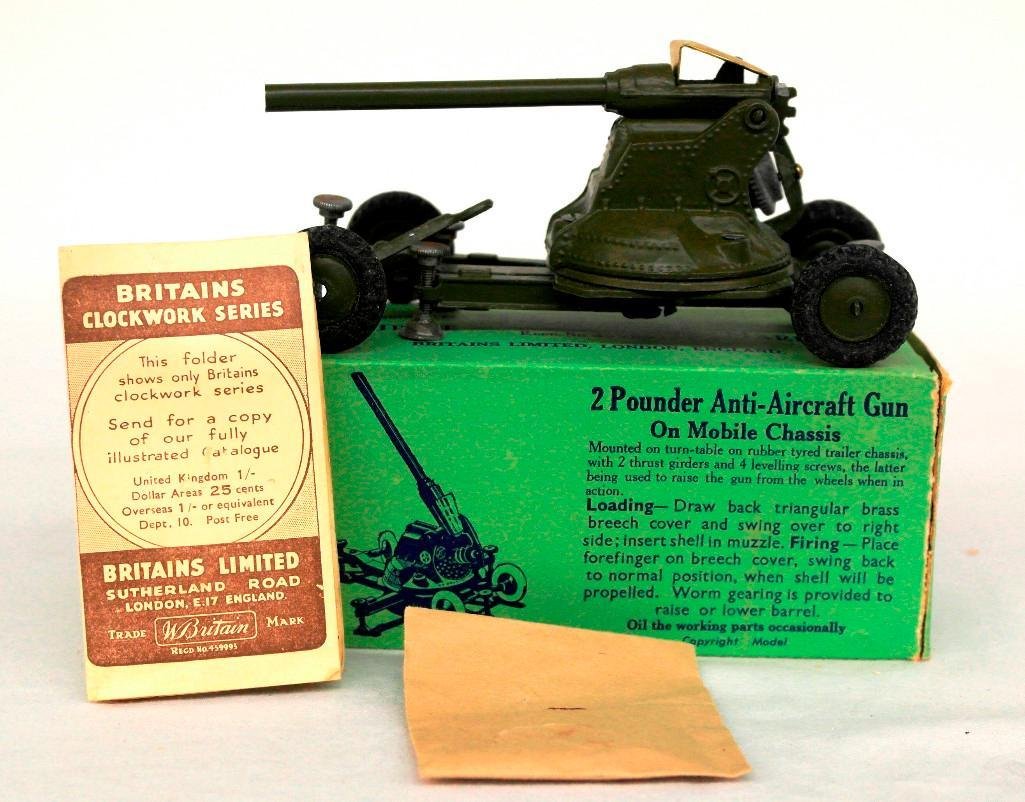 Britains #1717 - 2 Pounder Anti-Aircraft Gun in: This Britains gun is mounted on a mobile four-wheeled screwjack chassis. This olive-green gun has never been played with and comes complete in its original box with the catalog, shells, and packing ti