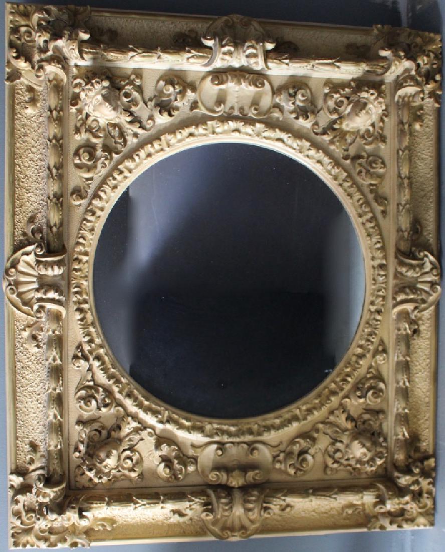 Carved Wood and Gesso Mirror: Exceptional carved wood and gesso mirror. The frame is 46" x 55" with round center mirror. Raised faces and ornamentation with very little gesso loss. May be hung horizontal or vertical. Good conditio