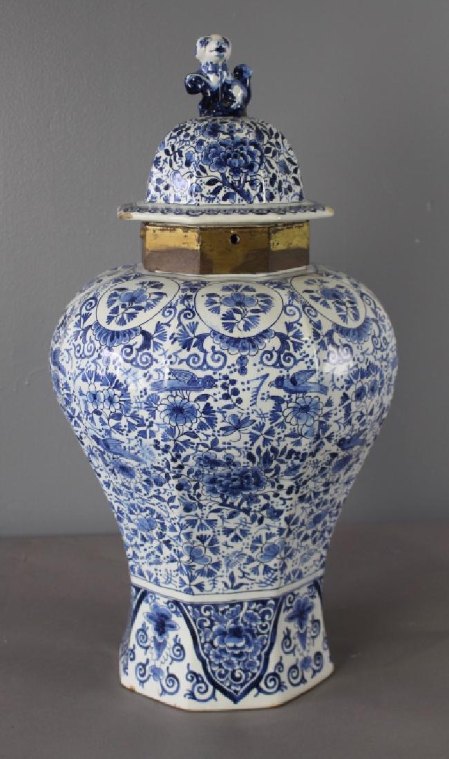 Delft Covered Jar, 18th Century: Delft covered jar, 18th century, condition issues: collar to jar has been reinforced with brass, 2 chips to led, makers initials on bottom, 23"h, 12" diameter.