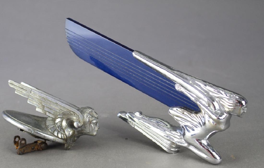 Two Automobile Ornaments: Two automobile ornaments: winged car mascot with cobalt Lucite attached wing to chrome 9" x 3.75" female (possibly Packard) with a chrome winged goddess with lion's head cowl radiator cap (one of wing
