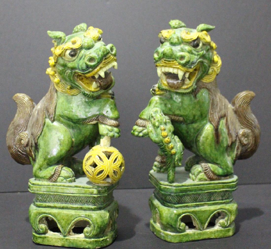 Pair Chinese Polychrome Temple Lions: Pair of Chinese polychrome temple lions on stands, both in excellent condition. One has lizard crawling on uplifted leg while the other stands over a reticulated ball on a slide, both with menacing sn