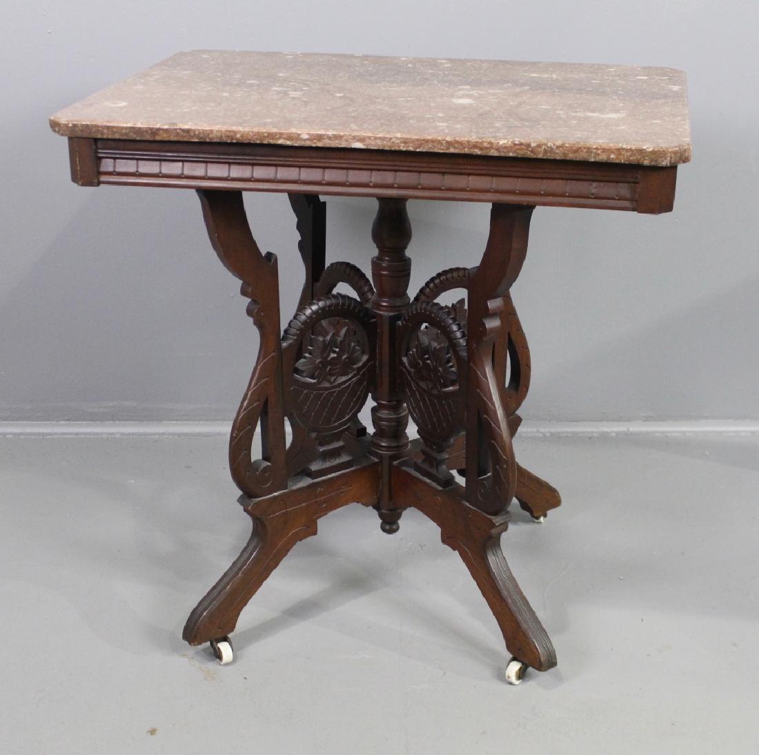 Victorian Marble Top Parlor Table: Victorian brown marble top parlor table, carved walnut base featuring floral baskets handles, original porcelain casters, very good condition, 30" x 30" x 21".