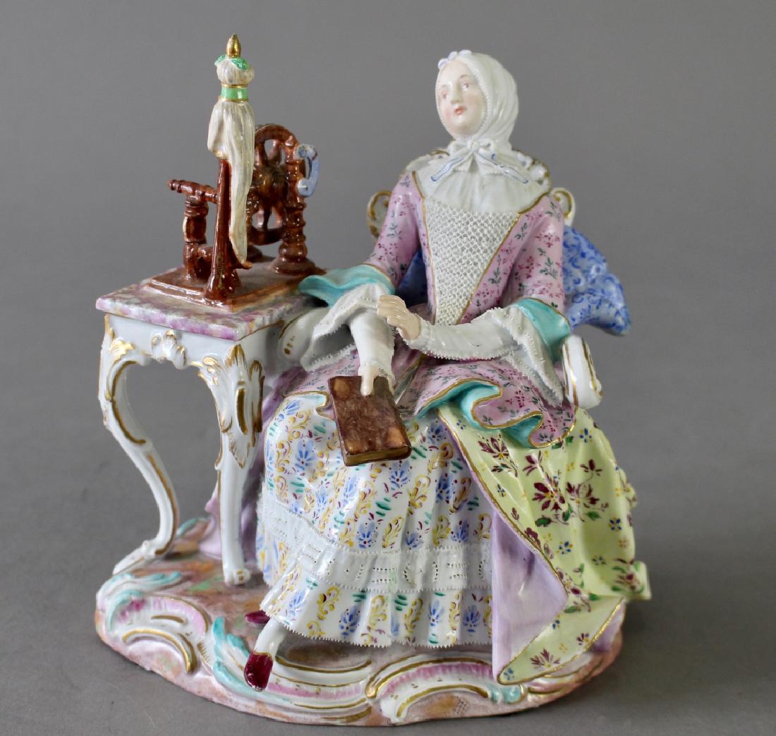 Meissen Figurine of Costumed Lady: Meissen porcelain figurine of costumed lady with head scarf sitting at sewing table and wheel. Hand dipped porcelain lace on dress and cuffs, many patterns of hand painted decoration, blue cross sword
