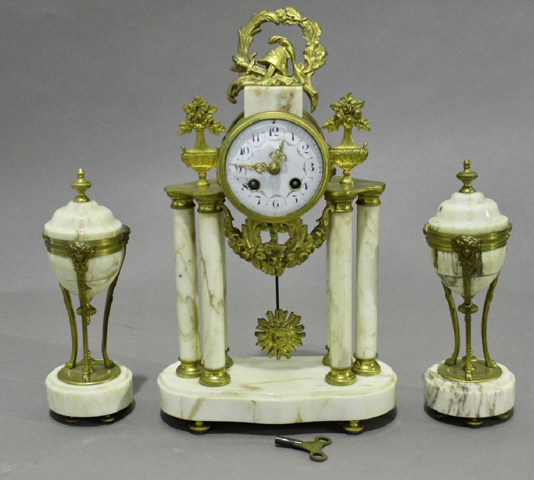 Japy Freres Empire French Clock & Garnitures: Japy Freres Empire style French clock, white marble columns hold a gilt metal housing with porcelain face, fine ormolu adornments, with pair of matching garnitures, excellent running condition, one co