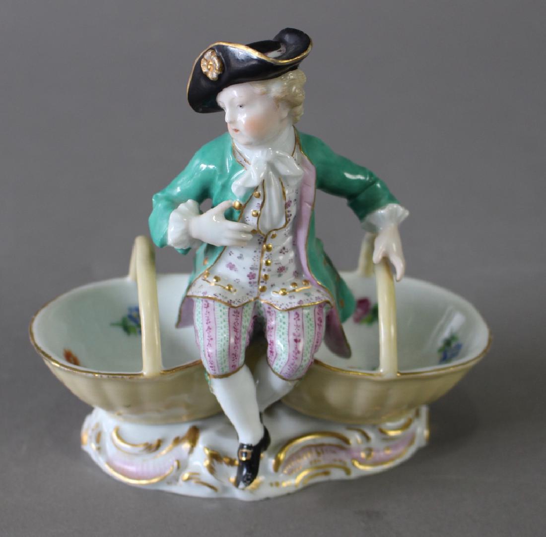 Meissen Figural Double Salt Cellar: Meissen figural double salt cellar, seated boy sitting on baskets, blue cross swords mark, 5.25"h x 5.5" x 3.25", two no harm flakes on underside.