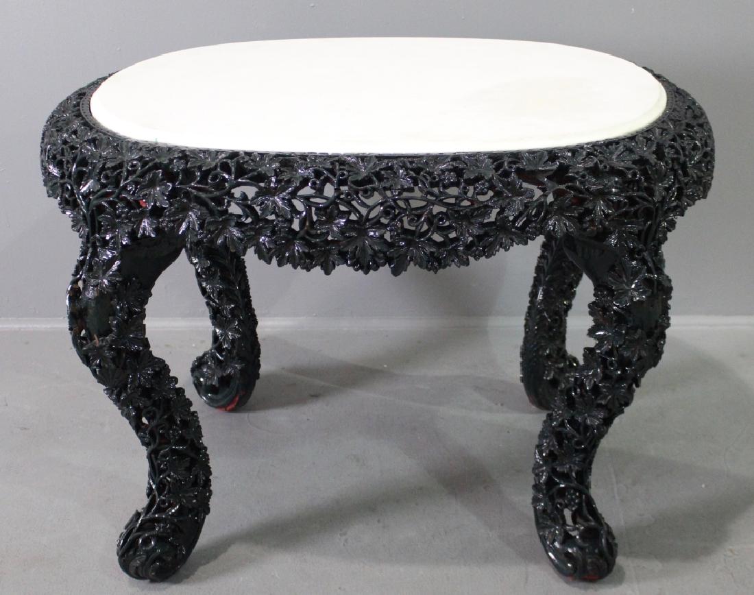 Burmese Teak Carved Marble Top Table: most unusual, c. 1880-90, bright white oval marble inset into a richly, deep and pierce carved base, in a high gloss dark green enamel finish, some loss of high points of 2 legs, virtually unnoticeabl