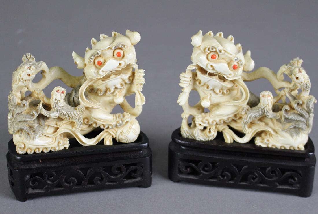 Pair Chinese Carved Foo Lions: Richly carved pachyderm material with cubs or pups on their backs, coral inset eyes, elaborate detail all over, each 3"h x 4" without stand. NOTE: This item may not be shipped out of the state of Flor