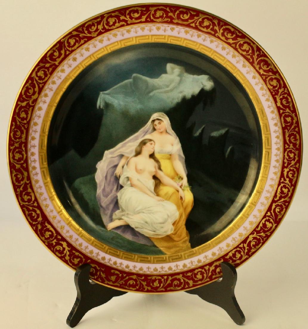 German Porcelain Scenic Portrait Plate: depicts two women, one resting on the other with dark craggy background with faint, one reclining woman on rocky slab, no apparent artist signature, blue beehive under glaze mark, triple border with m
