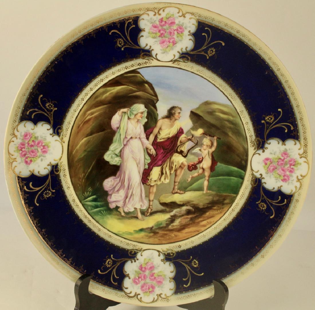 15" Scenic Portrait Charger: depicting man with harp and gowned woman being led by a putti with a torch, cobalt border with four medallions with roses, blue beehive mark under glaze, Bloch & Co Eichwald, Germany, c. 1900, very go