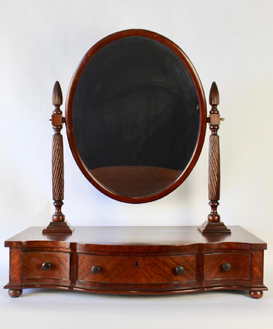 Antique Mahogany Shaving Stand: oval 25" mirror supported by twist carved harps and finials, serpentine 3 drawer front, 15" x 32", 36" overall height, good condition with one inch no see piece of veneer missing, c. 1920s.