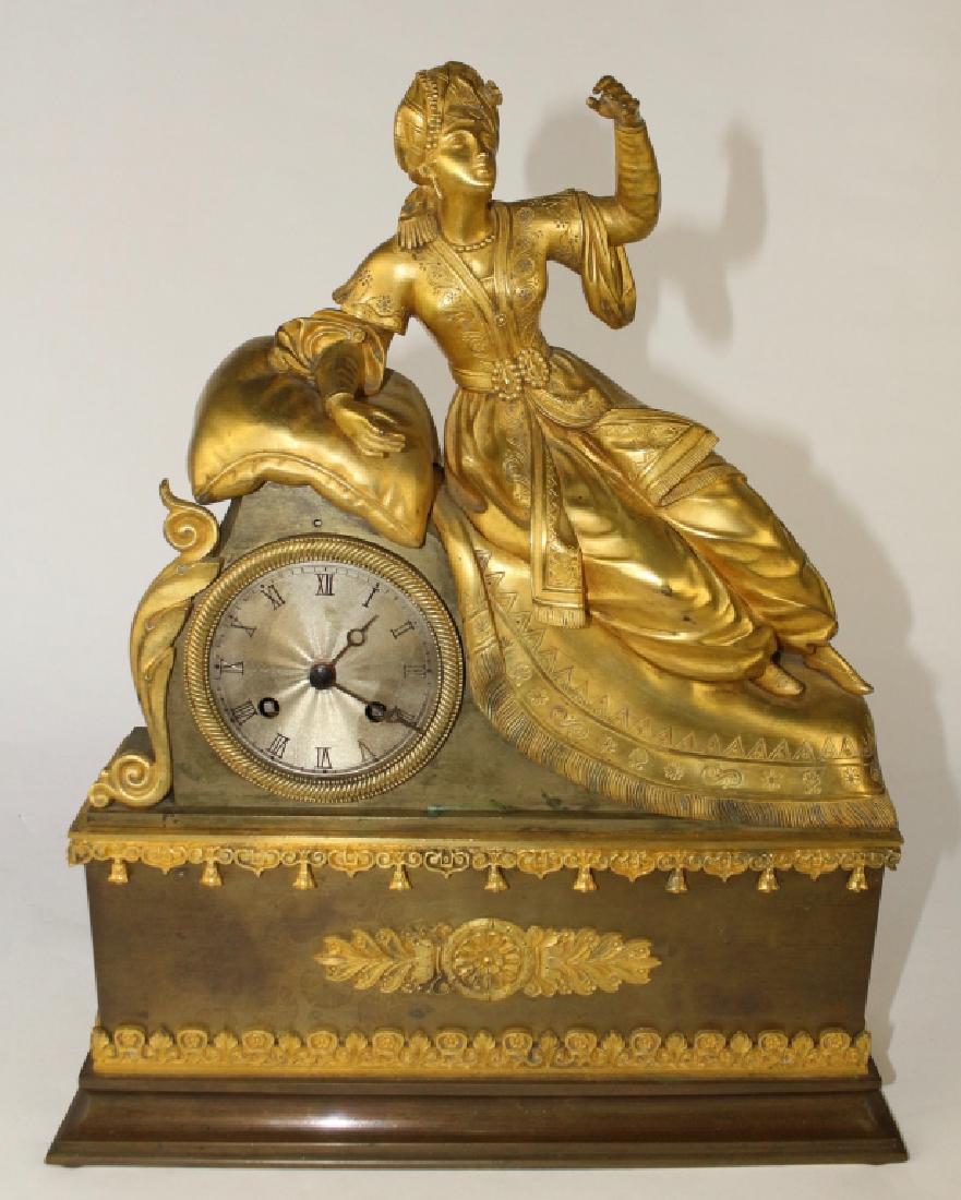 French Figural Mantle Clock: figure of woman in turban and long jacket resting on pillows, metal face with Roman numerals, bronze housing, works well, 16" x 13" x 4".