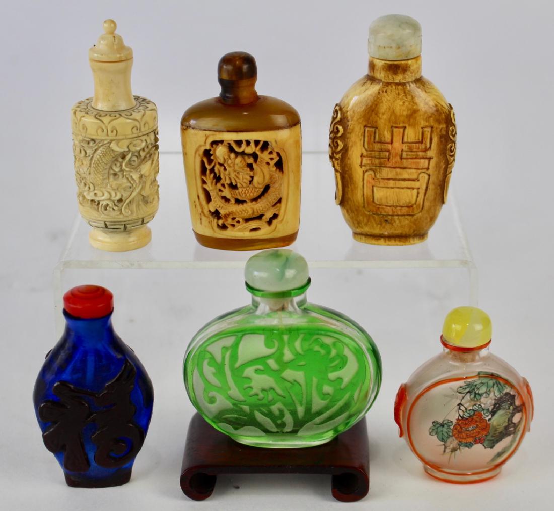Seven Chinese Snuff Bottles: Amber animal horn bottle with carved bone scene, signed. Dragon carved cylinder of pachyderm material. Carved hardstone example with calligraphy. A crystal bottle with interior decoration. Cobalt Peki
