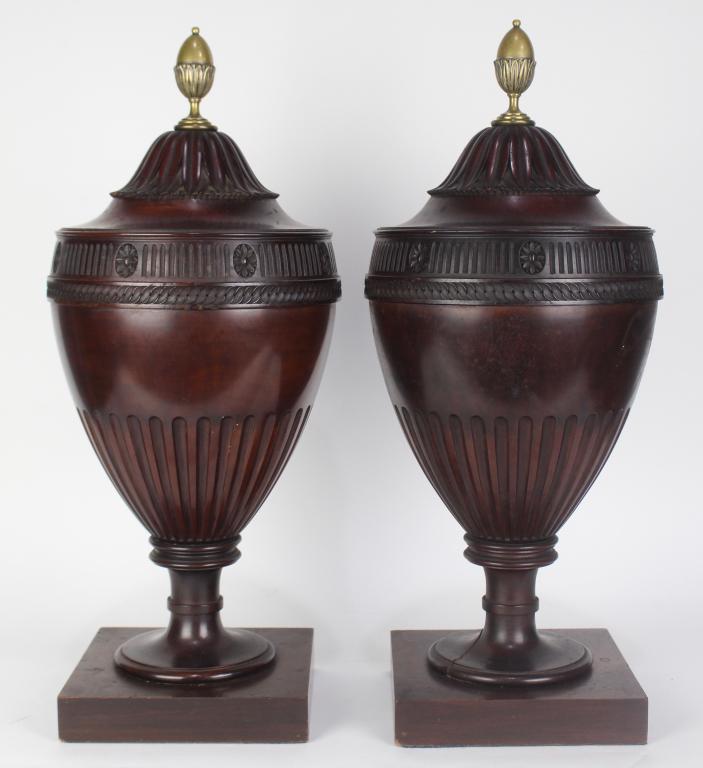 Pair Georgian Style Urn Form Knife Boxes: mid 19th century, mahogany urn shape knife boxes, brass finials, carved leaf top which slides on square post revealing slots, 8.5" plinths, fluted body, one has evidence of damage where it meets plint