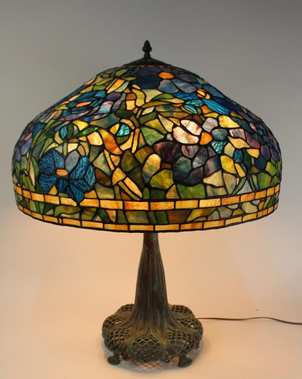 Leaded Glass Table Lamp: blue and green floral 24" diameter shade, resting on bronze reticulated Tiffany style base having verde-gris patina, adjustable height shaft, no damage found on any tile, 6 socket top, in-line switch,