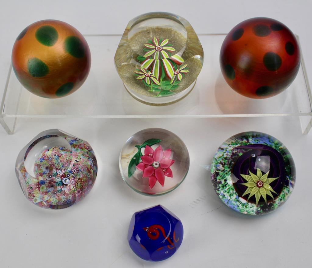 Group of Seven Paperweights: 1970 Baccarat with coiled snake and white poinsettia, a faceted micro-millefiori signed Baccarat, signed Ronald Hansen with red snake, an unsigned faceted example with red flower, and two iridescent s